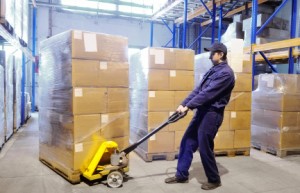 worker with fork pallet truck stacker in warehouse loading Group of cardboard boxes