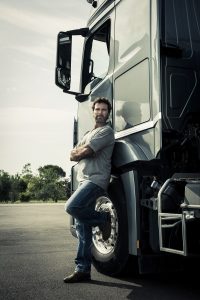 truck driver leaning against truck with arms crossed