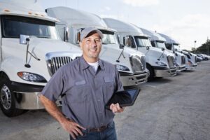 Big rig trucks behind man holding tablet